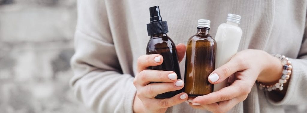 Woman holding amber bottles of personal care products.