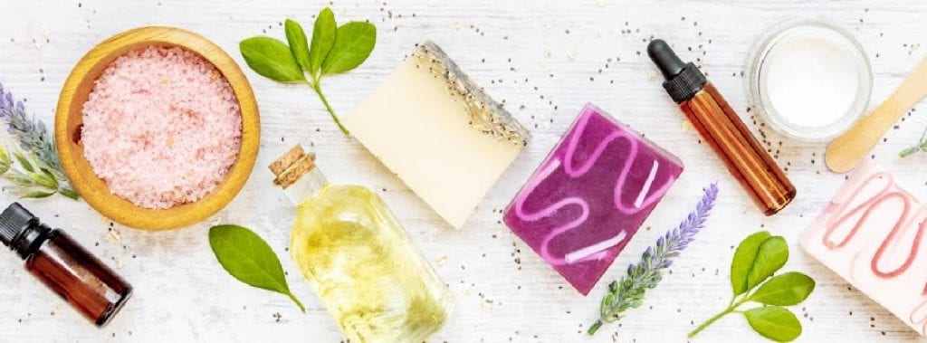 Colorful handmade skin care products such as soap, face serums, bath salts, and creams.