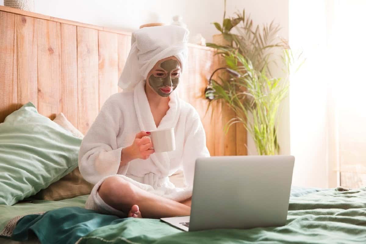 Woman sitting on bed finding the perfect skin care hashtags for Instagram