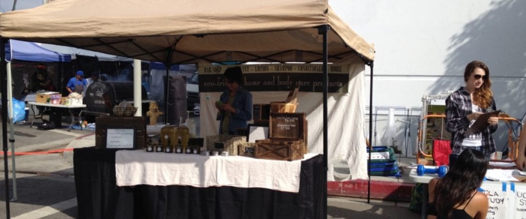 Booth set up at a farmers market or craft fair selling handmade skin care items.