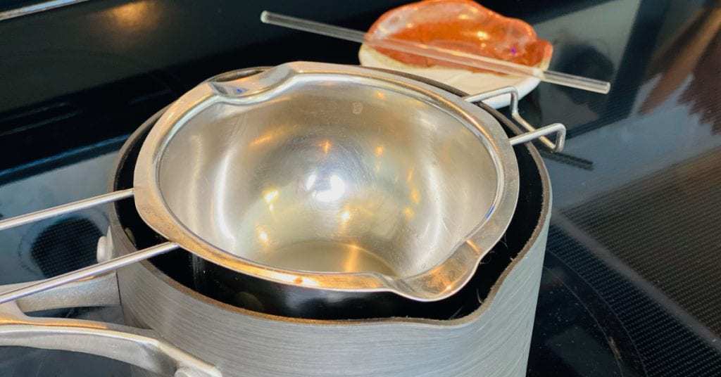 Pot sitting on stove, filled with a couple inches of water, double boiler sitting on top to make belly balm.
