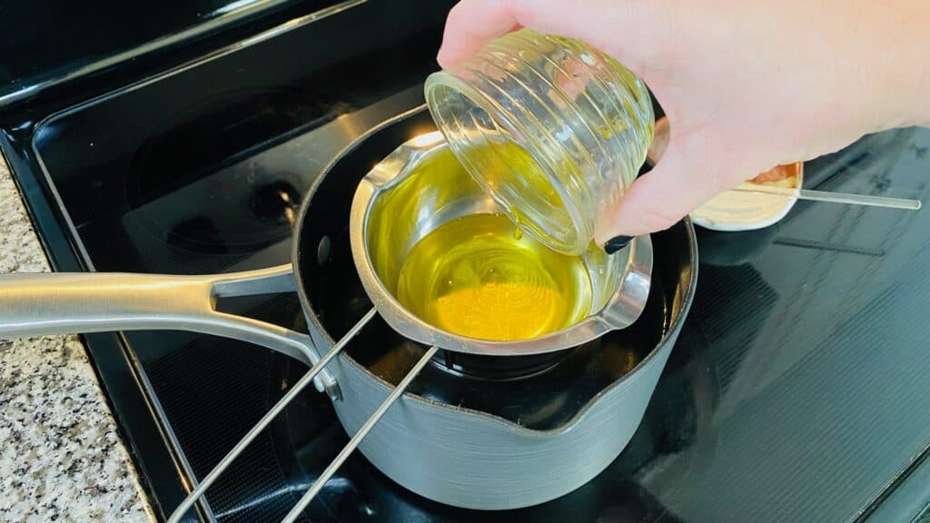 Adding rosehip oil to the melted beeswax and coconut oil.