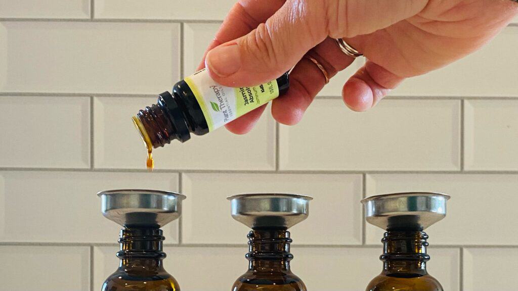 Adding essential oils to amber dropper bottles for a dry facial serum formulation.