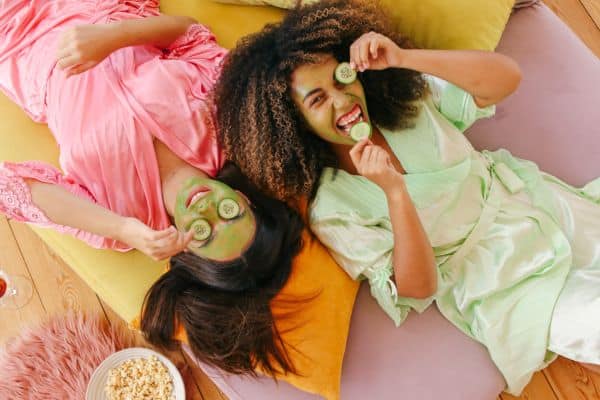 Holistic Skincare Featured Image with two woman in face masks eating cucumbers and smiling
